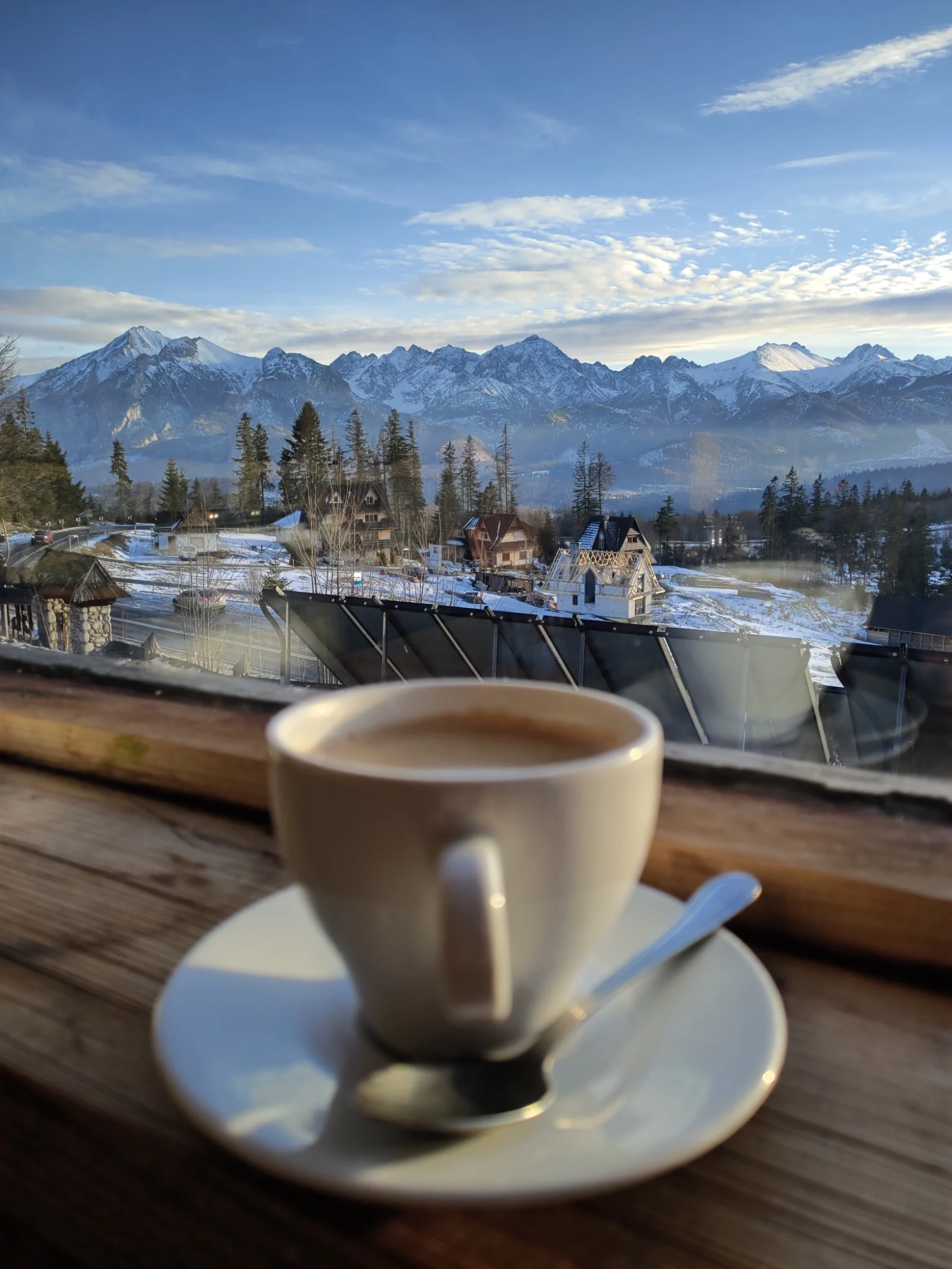 Cup of coffee by a window overlooking snowy Tatra Mountains