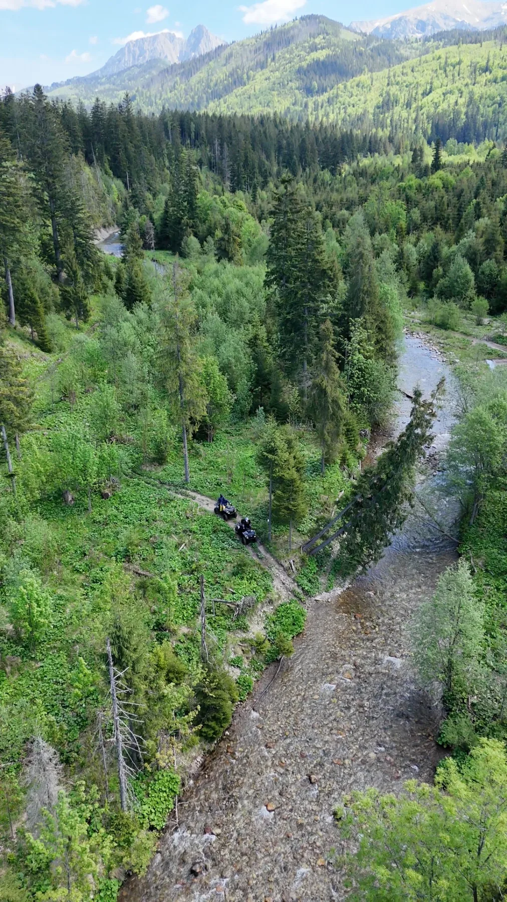 Aerial view of quad bikes following a trail beside a mountain river in the Tatras