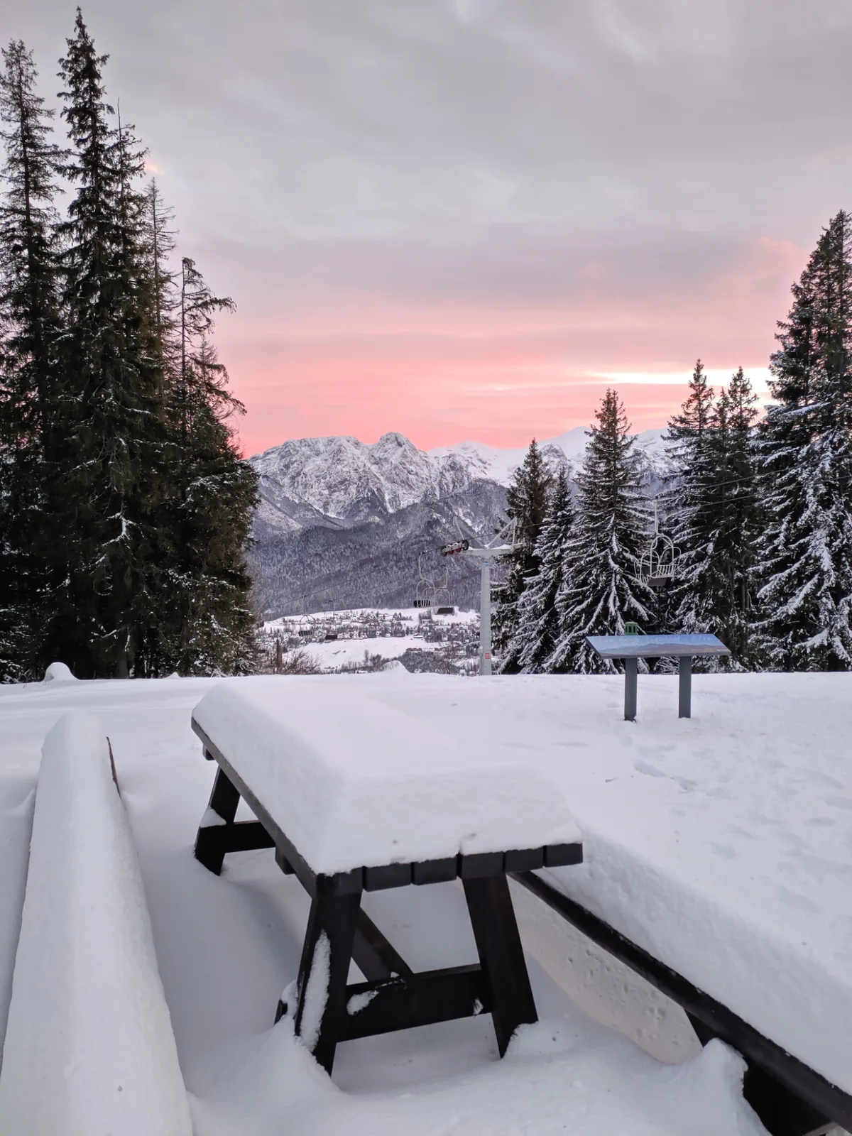 Snow-covered picnic tables overlooking the Tatras at sunset