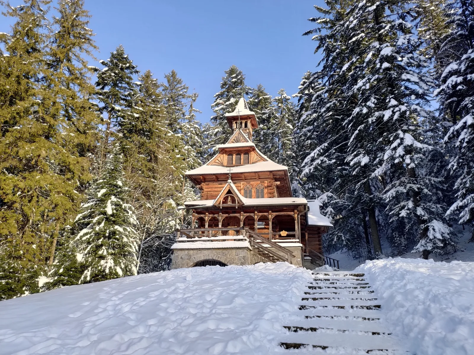 Wooden chapel surrounded by snow-covered trees in Zakopane